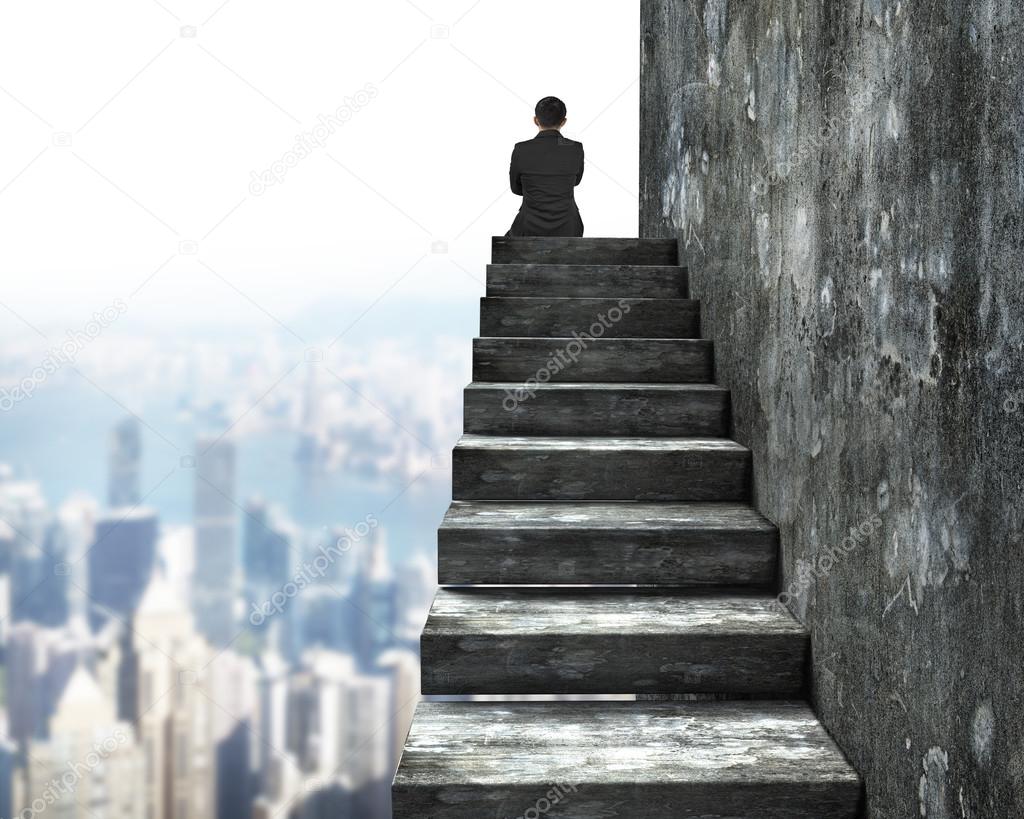 Rear view of man sitting on top of concrete stairs