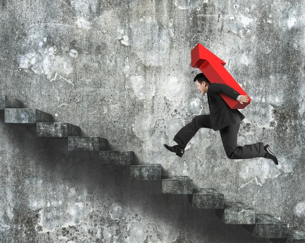 Empresario llevando un cartel de flecha roja corriendo por las escaleras —  Fotos de Stock