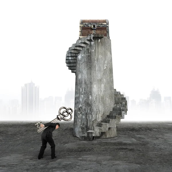 Man carrying key toward treasure chest — Stock Photo, Image