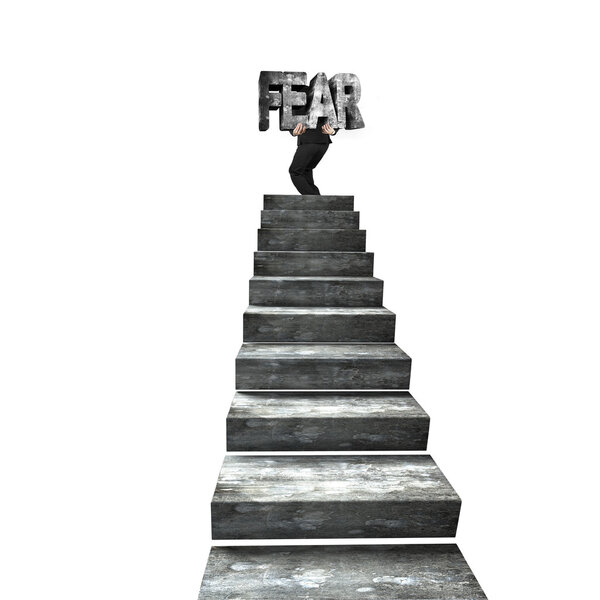 Businessman carrying big 3D fear concrete word on top of concrete stairs, isolated on white background.