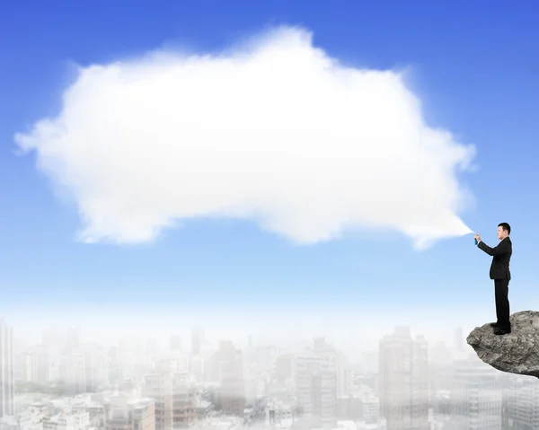 Hombre rociando pintura de nubes blancas en el acantilado — Foto de Stock