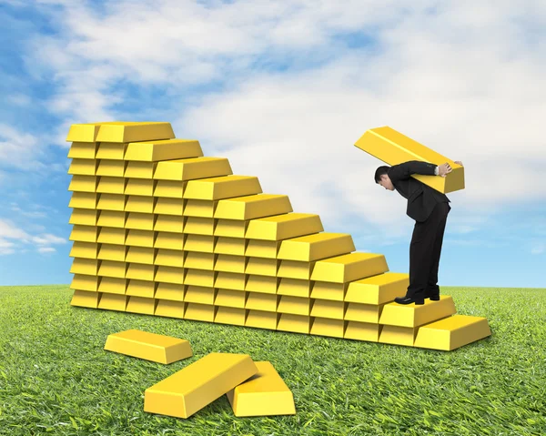 Empresario cargando lingotes subiendo escaleras doradas — Foto de Stock