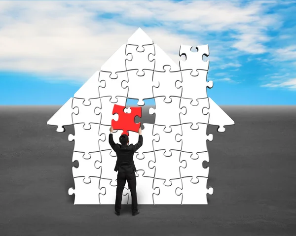 Assembling last red puzzle into house shape — Stock Photo, Image