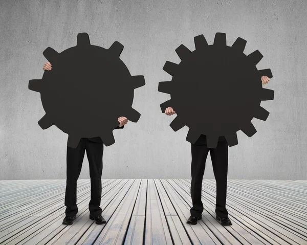 Businessmen hold their different gear on wooden floor — Stock Photo, Image