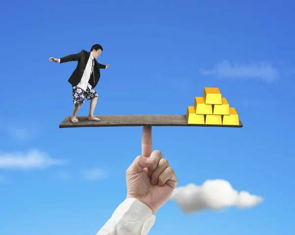 Man standing on finger seesaw vs stack of gold — Stock Photo, Image