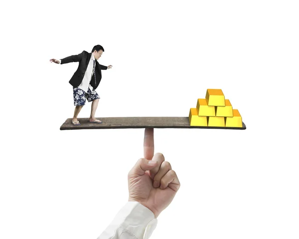 Affärsman står på finger gungbräda vs stack av guld — Stockfoto