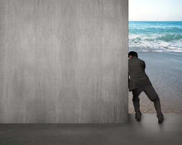 Businessman pushing gray concrete wall away — Stock Photo, Image