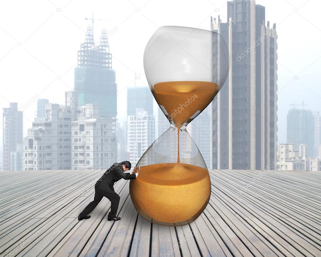 Businessman pushing tilt hourglass