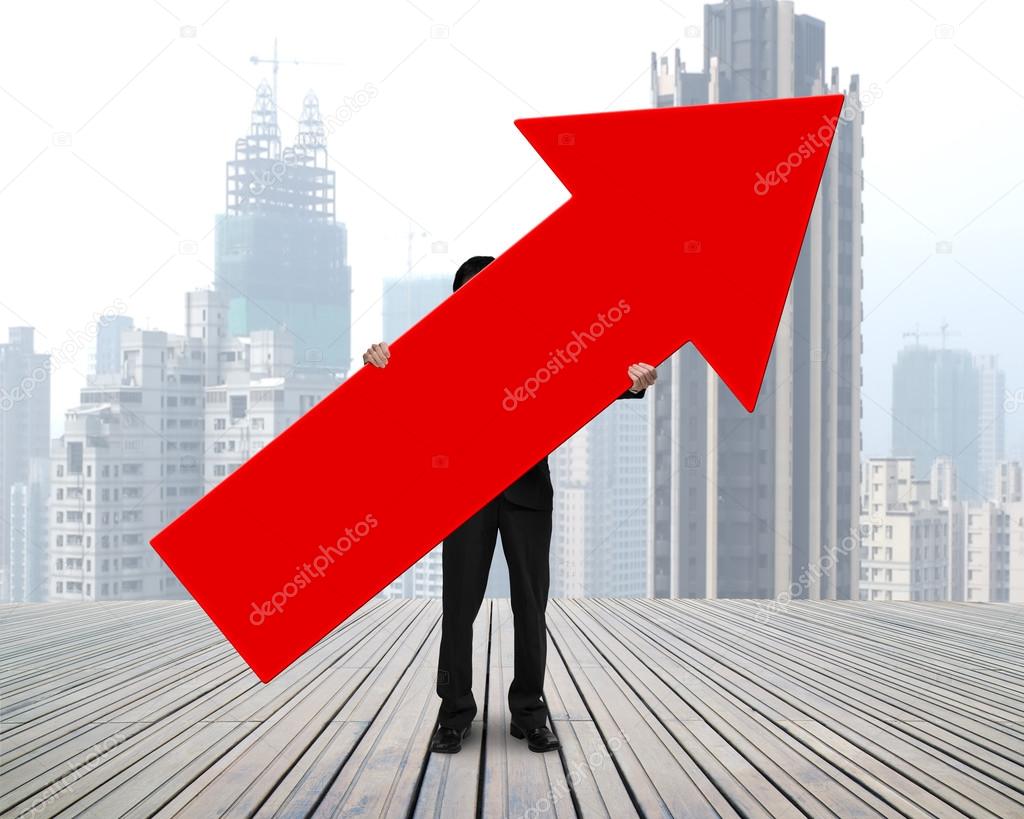 standing businessman holding red arrow sign