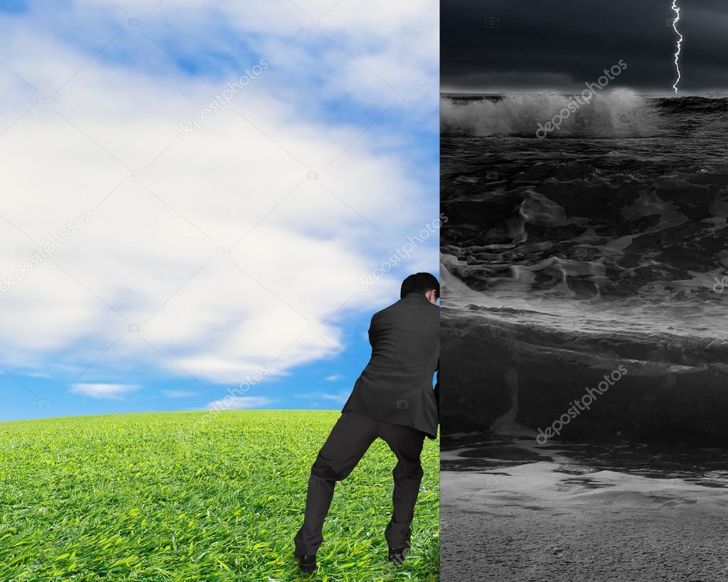 businessman pushing away stormy sea wall