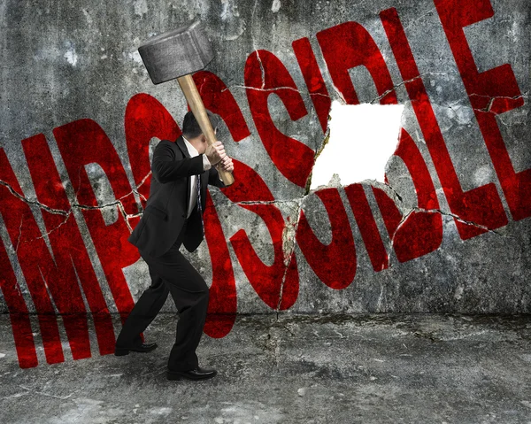 Businessman holding sledgehammer hitting red impossible word on — Stock Photo, Image