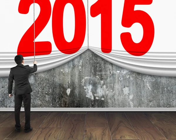Businessman pulling down 2015 curtain to cover mottled concrete — Stock Photo, Image