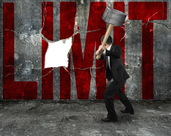 Businessman holding sledgehammer hitting red LIMIT word on concr — Stock Photo, Image