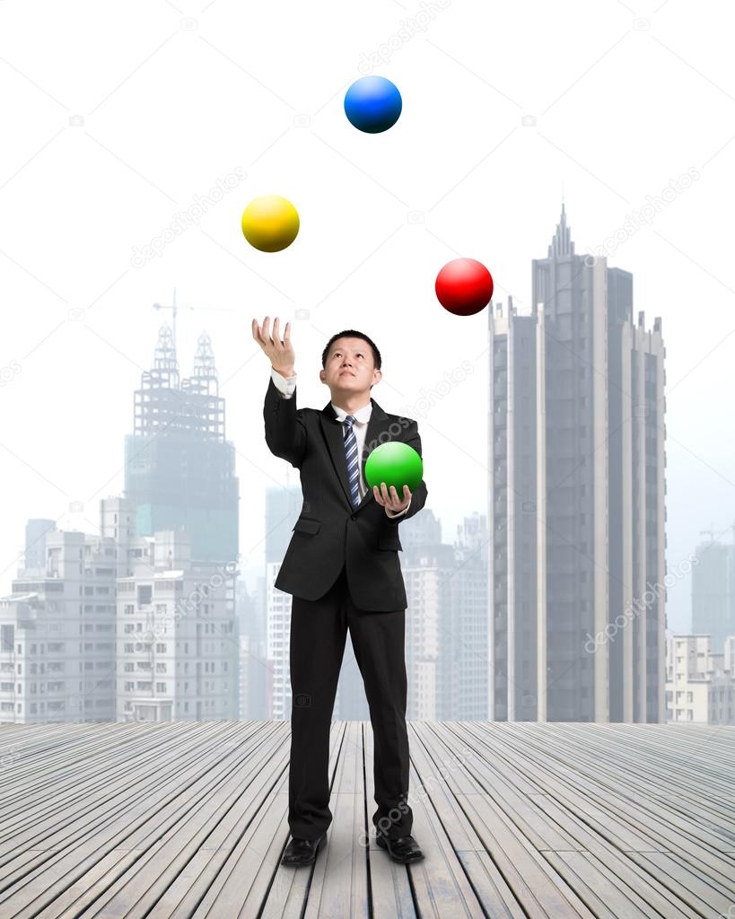 businessman throwing and catching colorful balls