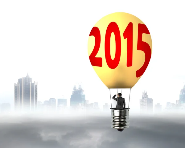 Homem de negócios em lâmpada brilhantemente amarelo 2015 balão de ar quente voando — Fotografia de Stock