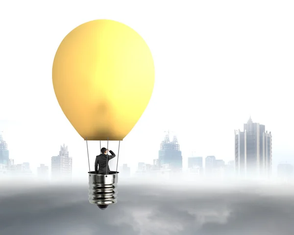 Businessman in brightly yellow lamp hot air balloon flying — Stock Photo, Image