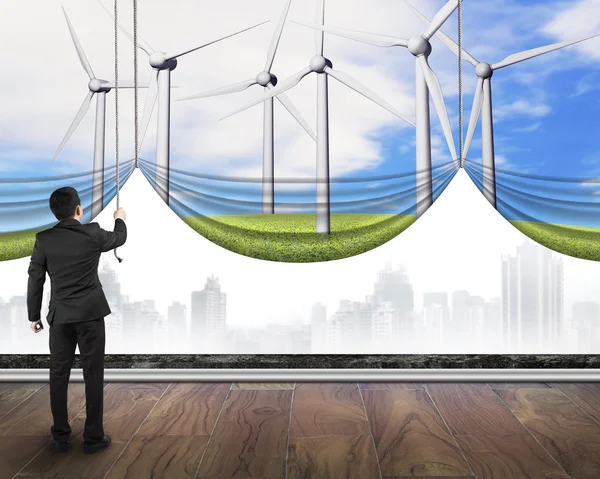 Businessman pulling open wind turbines curtain covered gray city — Stock Photo, Image