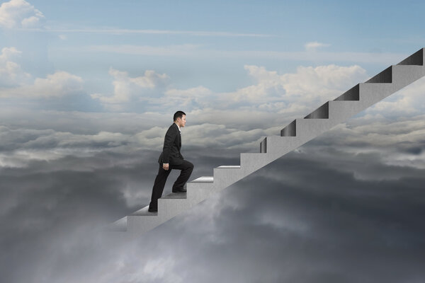 бизнесмен взбирается по бетонной лестнице с естественным облачным небом
 