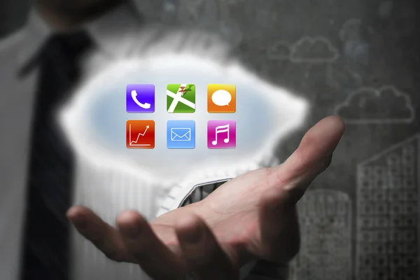 Businessman showing colorful app icons on cloud with doodles wal — Stock Photo, Image