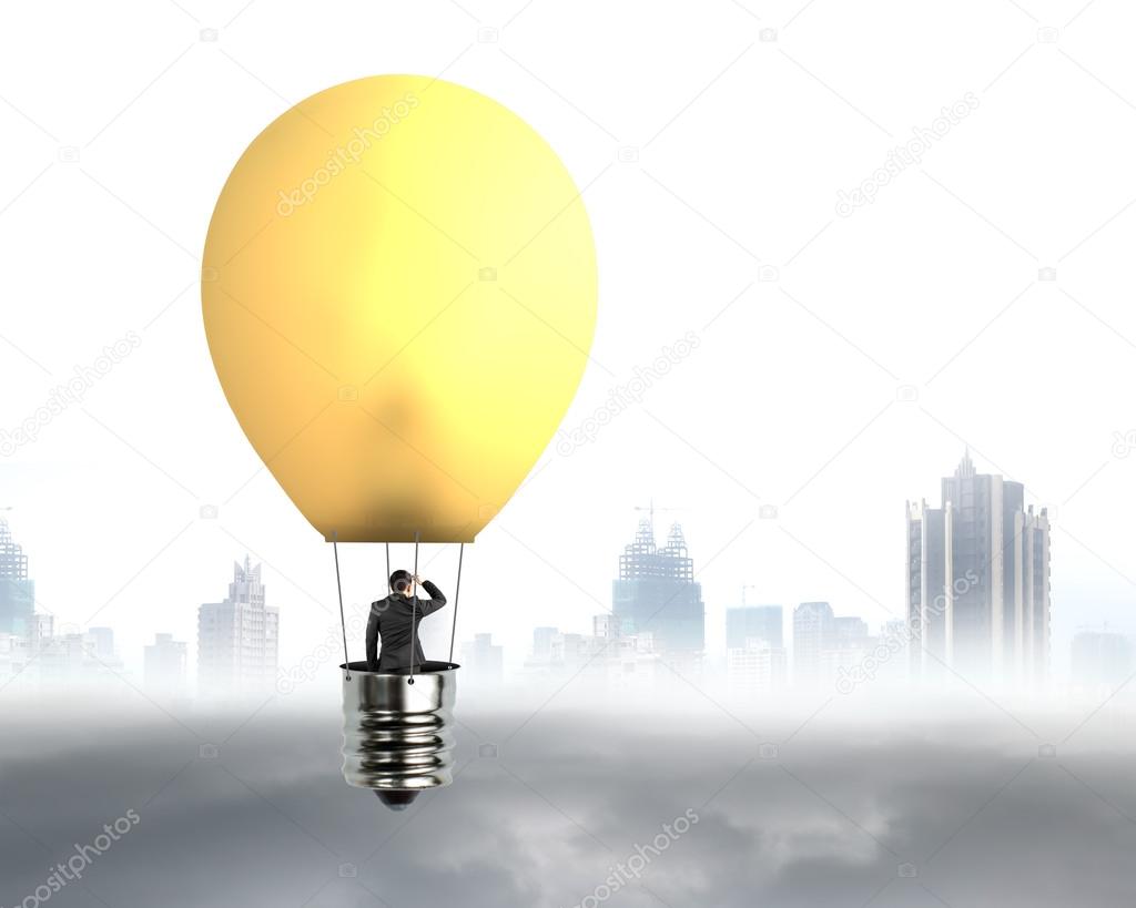businessman in brightly yellow lamp hot air balloon flying