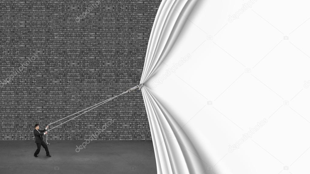 businessman pulling down white curtain covering old dark brick w