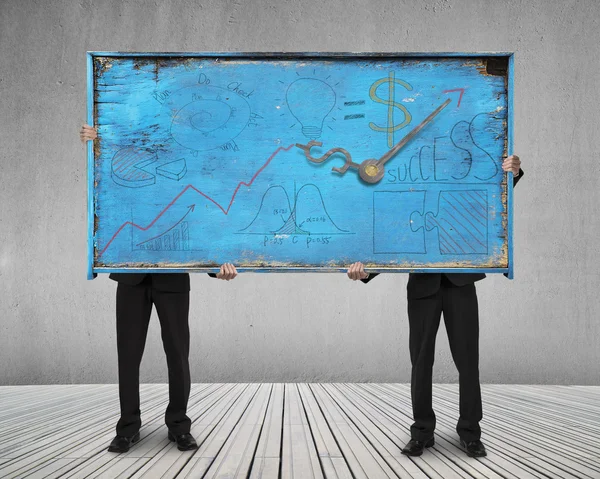 Two men holding old blue doodles billboard on wooden floor — Stock Photo, Image