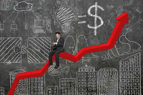 Affärsman med tablett på röda trenddiagram med doodles vägg — Stockfoto