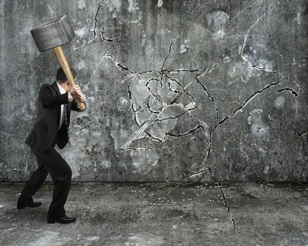 Geschäftsmann bricht mit Vorschlaghammer Mauer auf Beton — Stockfoto