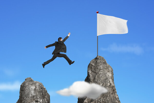 businessman jumping over mountain peak to blank flag with sky