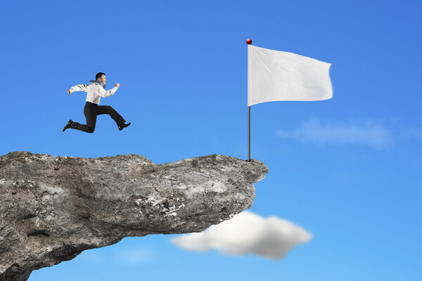 man running to blank white flag on cliff with sky