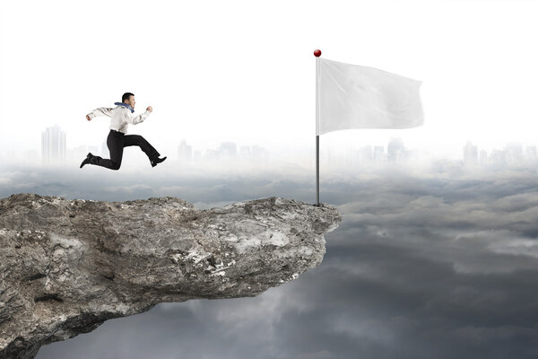 man running to white flag on cliff with cloudy cityscape