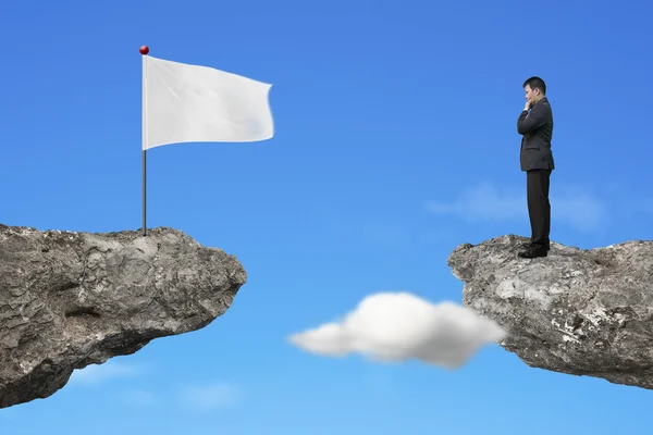 Gestionnaire debout sur une falaise avec un drapeau blanc blanc blanc et le ciel — Photo