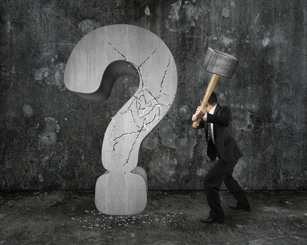 Businessman holding hammer cracked question mark with dark mottl — Stock Photo, Image
