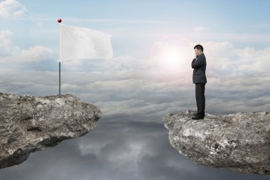 Manager standing on cliff with blank flag and sunlight cloudscap