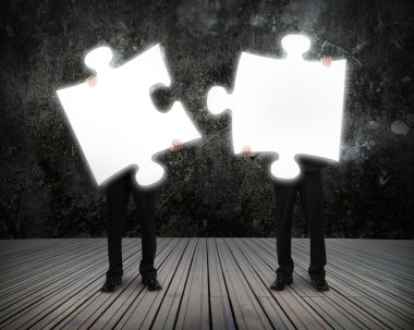 Glowing puzzles businessmen hold to connect illuminating dark wo clipart