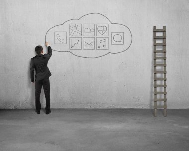 Businessman standing and drawing app icon on concrete wall