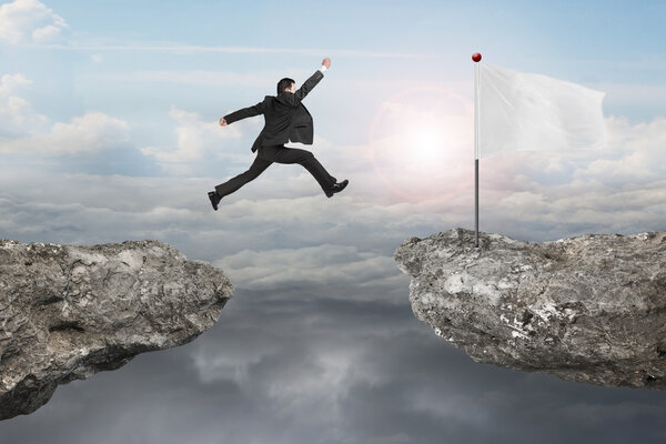 Businessman jump on cliff with blank flag and sunlight cloudscap