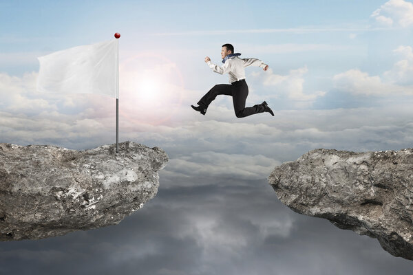 Man jumping on cliff with blank flag and sunlight cloudscapes