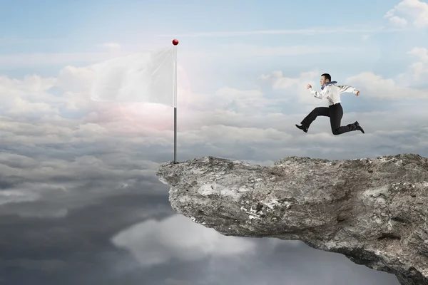 Man running to blank white flag on cliff with sunlight — Stock Photo, Image