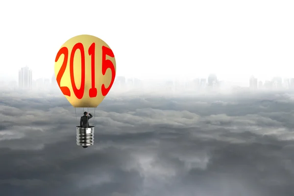 Businessman take 2015 bulb-shaped hot air balloon with cityscape — Stock Photo, Image