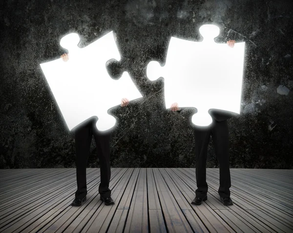 Glowing puzzles businessmen hold to connect illuminating dark wo — Stock Photo, Image