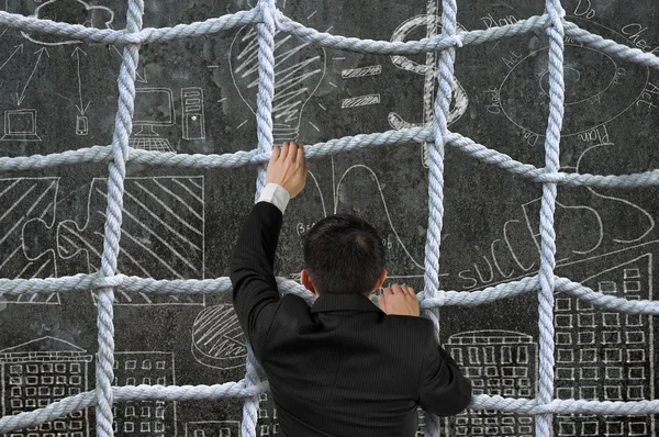 Hombre de negocios escalando la red de cuerda entrecruzada en el concepto de negocio doo — Foto de Stock