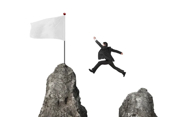 Businessman jumping over mountain peak to blank white flag — Zdjęcie stockowe