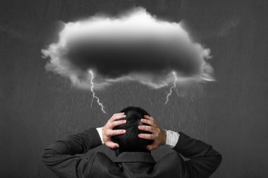 Depressed businessman with dark cloud rain lightning over his he