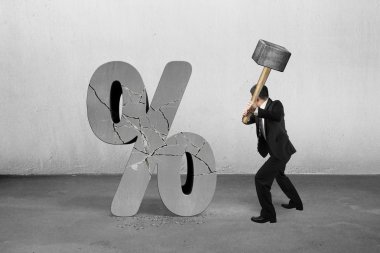 Businessman holding sledgehammer hitting cracked percentage sign