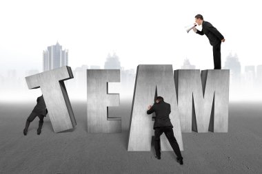 Businessman commanding employees to move TEAM word together with