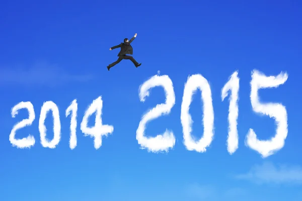 Бизнесмен прыгает через облако формы 2015 года на голубом небе — стоковое фото