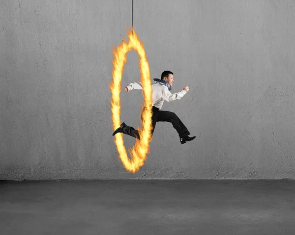 Man jumping through fire hoop with concrete wall — Stock Fotó