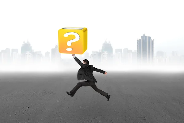 Jumping businessman hitting 3d question mark box with cityscape — Stock Photo, Image