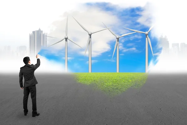 Бизнесмен, распыляющий краской ветряные турбины, покрыл серый городской пейзаж — стоковое фото